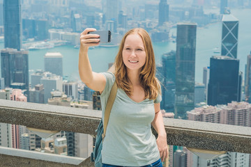 Hong Kong Victoria Peak woman taking selfie stick picture photo with smartphone enjoying view over...