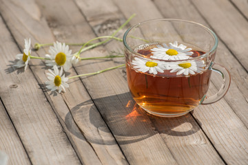 Herbal tea with chamomile on a wooden table on a summer sunny morning