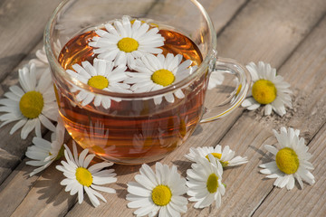 Obraz na płótnie Canvas Herbal tea with chamomile on a wooden table on a summer sunny morning