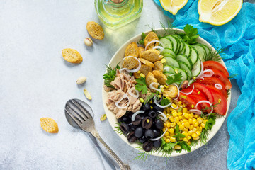 Summer Salad with vinaigrette salad dressing. Salad with tuna, fresh vegetables, pistachios and greens on a gray stone background or slate. Top view. Copy space.