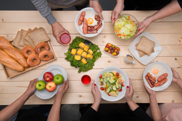 Enjoying dinner with friends.  Top view of group of people having dinner together while sitting at wooden table © makistock