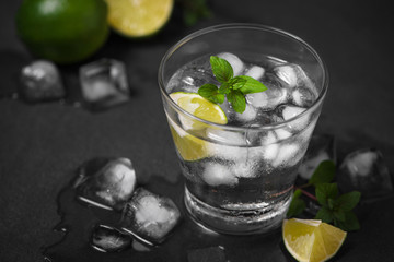 Mojito cocktail with lime and mint in glass on a grey stone background