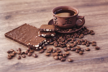 roasted coffee beans with chocolate and nuts on a wooden surface.