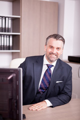 Attractive adult businessman at his desk in office. Business and corporate. Confident CEO