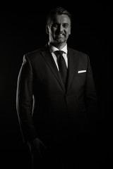 Portrait of adult confident businessman in studio photo on black background in black an white