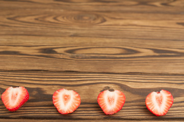 Row of bisected fresh strawberry on old wooden planks