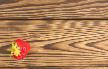 Single fresh ripe strawberry on old rustic planks