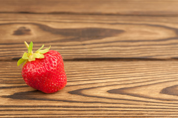 Single fresh ripe strawberry on old rustic planks