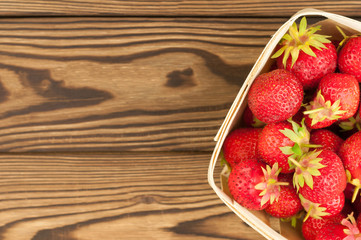 Strawberries in wicker basket on rustic wooden background