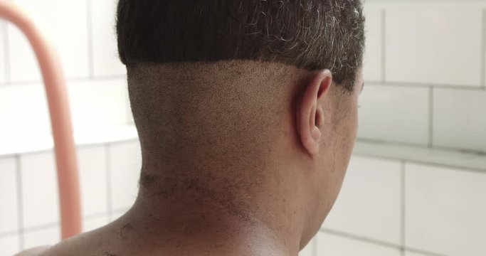 mixed race man has a haircut at home in sunny bathroom