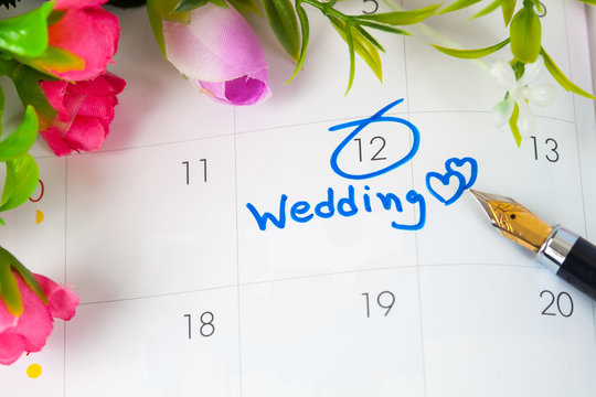Wedding note on a calendar sets a reminder for the wedding day with flower and pen