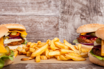 Tasty home made burgers on wooden plate next to fries. Fast food. Unhealthy snack
