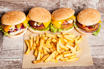 Tasty home made cheeseburgers on wooden plate next to fries. Fast food. Unhealthy snack