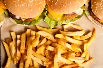Tasty home made cheeseburgers on wooden plate next to fries. Fast food. Unhealthy snack