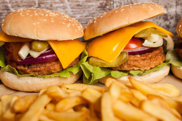 Tasty home made cheeseburgers on wooden plate next to fries. Fast food. Unhealthy snack