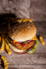 Tasty burgers on wooden plate next to fries. Fast food. Unhealthy snack