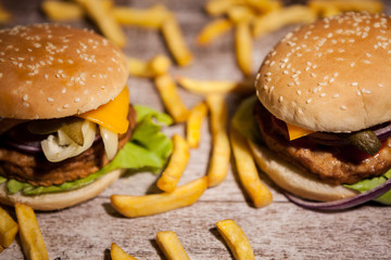 Classic home made burgers on wooden plate next to fries. Fast food. Unhealthy snack