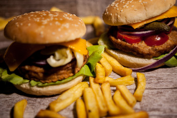 Classic home made burgers on wooden plate next to fries. Fast food. Unhealthy snack