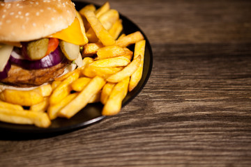 Delicious home made burgers on black plate next to fries. Fast food. Unhealthy snack