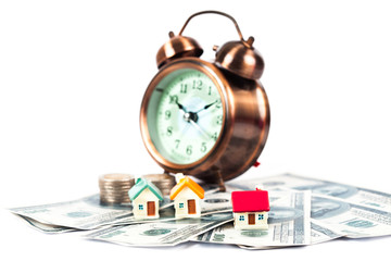 mini house on coin stack with alarm clock.