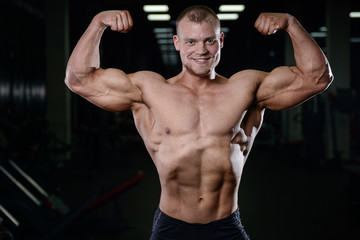 Fototapeta premium Caucasian handsome fitness model training in the gym. Man on diet flexing muscles