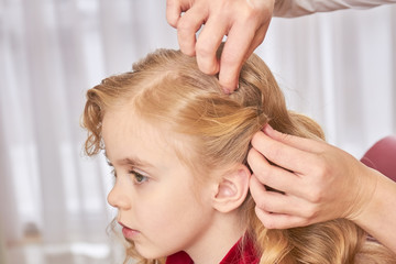 Little girl, hands of hairdresser. Face of child, side view.