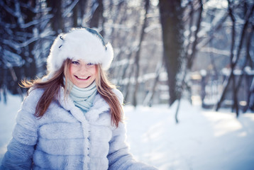 Fototapeta na wymiar Beautiful girl in a winter snowy park