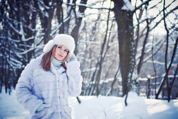 Fototapeta na wymiar Beautiful girl in a winter snowy park