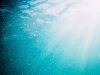 Fototapeta na wymiar Underwater turquoise texture and sun rays in ocean