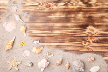 Seashells with beach sand on brown wooden table