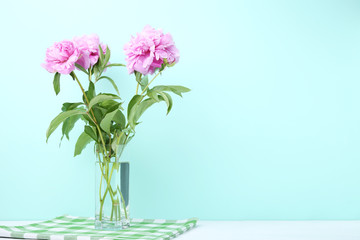 Bouquet of peony flowers in vase on mint background