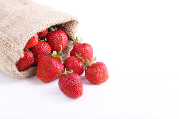 Fresh strawberries with sackcloth on white wooden table