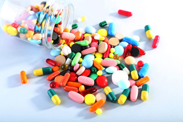 Colorful pills in glass jar on grey background