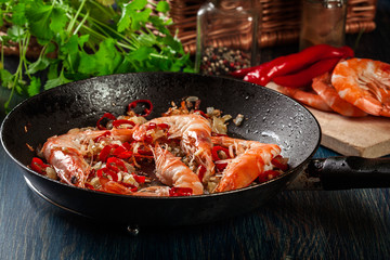 Shrimps roasted on frying pan with onion, garlic and chili
