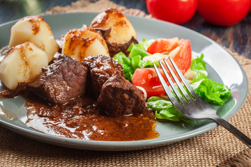 Pork meat stew served with potatoes and vegetable salad