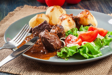 Pork meat stew served with potatoes and vegetable salad