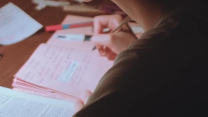 Young woman sitting at the table and work. Indoors study for exams in low light room. - Powered by Adobe