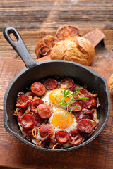 Fried eggs with sausage and onion on frying pan