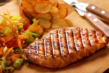 Grilled chicken breast fillet with potato chips and salad
