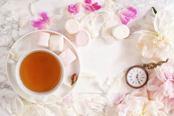 Obraz na płótnie Canvas Tea time. Flat lay over light background with peonies, marshmalows and cup of tea