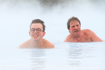 Young men relaxing in blue waters from a hot spring with sulfur and silica in Iceland