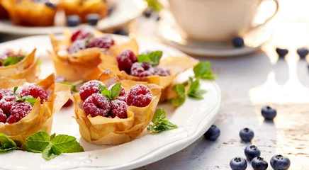 Fotobehang Dessert Phyllo cups with Mascarpone cheese filling topped with fresh Raspberries and mint on a white plate, delicious dessert