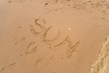 Sun word on sand on the the beach as background. Summer time