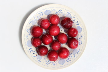 Red plums on a plate with a pattern
