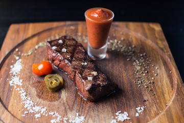 Beef steak with grilled vegetables and seasoning on serving board block