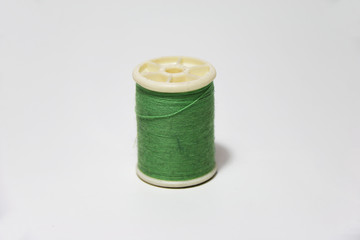 Green thread in the thread roll on white background. Through the use already from sewing garment.