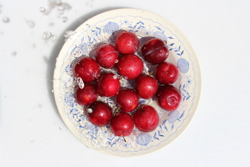 Red plums on a plate with a pattern