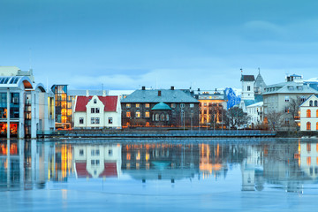 Beautiful reflection of the parliament house Althing of Reykjavik in lake Tjornin at the blue  - obrazy, fototapety, plakaty