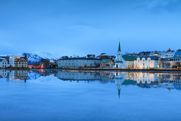 Beautiful reflection of the cityscape of Reykjavik and the Free church in lake Tjornin at the blue hour in winter