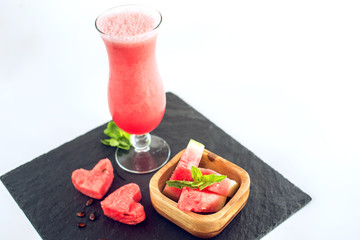 Fresh red smoothie in a glass with sliced pieces of watermelon and mint on white isolated background. Summer cool drinks